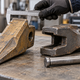 A generic excavator bucket tooth, adapter and retaining pin beside a caliper on a workshop bench.
