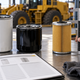 Generic spin-on and cartridge oil filters beside a caliper and blank catalog sheet on a workshop bench.